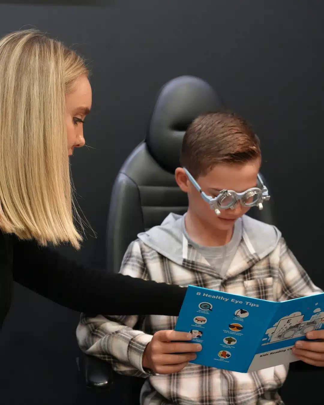Optometrist reviewing a healthy eye tips pamphlet with a young boy wearing trial frames at Reza Ferreira Optometrist